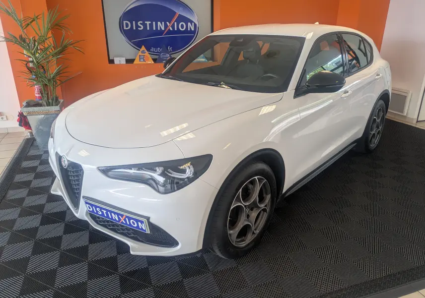 Vue 3/4 avant droite d'un Alfa Romeo Stelvio blanc 2023 avec jantes distinctives et calandre caractéristique.