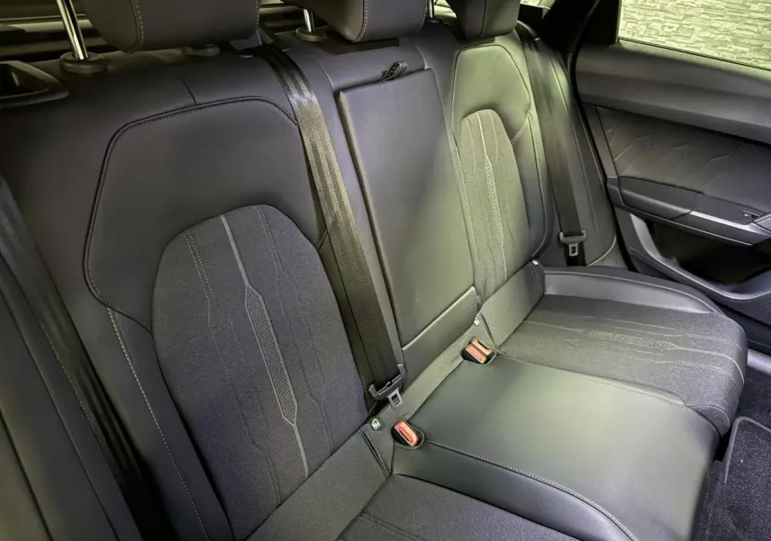 Vue rapprochée des sièges arrière noirs en similicuir et tissu du CUPRA Leon Sportstourer 2024 avec ceintures de sécurité visibles.