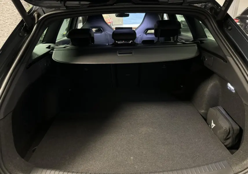 Coffre ouvert du CUPRA Leon Sportstourer gris, vue arrière montrant l'espace de chargement et les sièges baquets noirs.