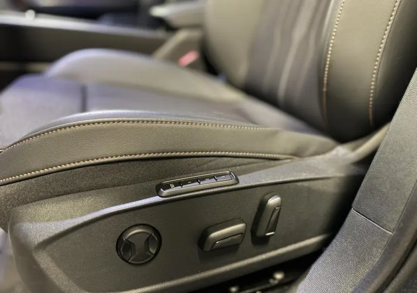 Gros plan sur les commandes de réglage électrique du siège avant droit du CUPRA Leon Sportstourer gris 2024.