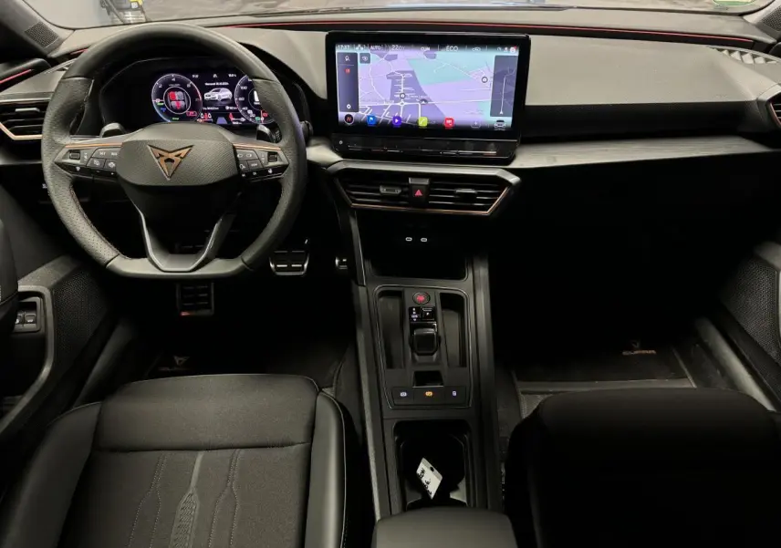 Vue intérieure avant du CUPRA Leon Sportstourer 2024 avec tableau de bord digital et écran tactile central.