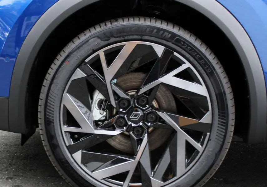 Gros plan sur la roue avant gauche du Renault Captur bleu Iron Metal avec jante alliage noire et argentée au design géométrique.