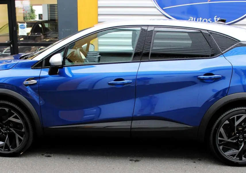 Profil côté gauche d'un Renault Captur 2025 bleu Iron Metal avec toit gris et jantes noires stylisées.