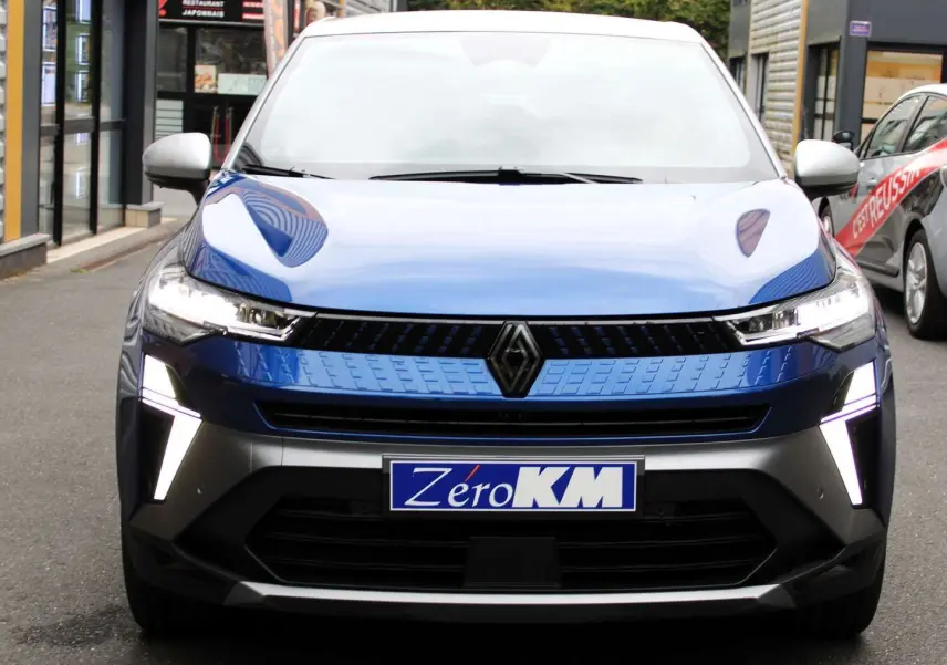 Vue frontale du Renault Captur 2025 bleu Iron Metal avec toit gris et feux LED en forme de V allumés.