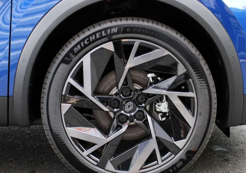 Gros plan sur la roue avant droite du Renault Captur bleu Iron Metal avec jante alliage noir et argent.