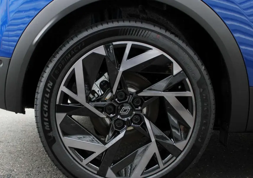 Gros plan sur la roue avant gauche du Renault Captur bleu Iron Metal avec jante alu bicolore au design géométrique.