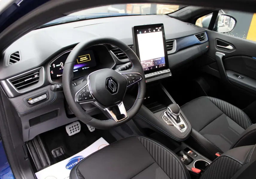 Intérieur du Renault Captur 2025, vue côté conducteur, tableau de bord moderne avec écran tactile vertical et sellerie noire.