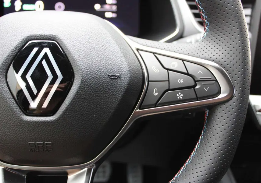 Gros plan sur le volant en cuir perforé avec commandes intégrées du Renault Captur hybride 2025, finition Esprit Alpine.