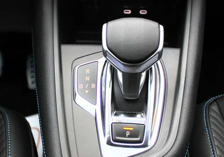 Le levier de vitesses automatique du Renault Captur 2025, entouré de cuir noir avec surpiqûres bleues.