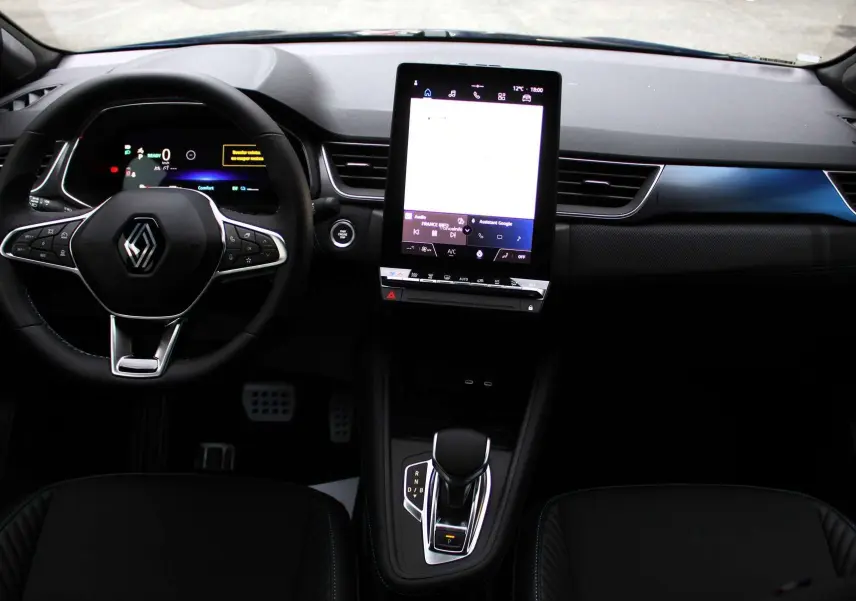 Intérieur Renault Captur 2025 vu de face, tableau de bord noir avec écran tactile vertical et volant multifonction.