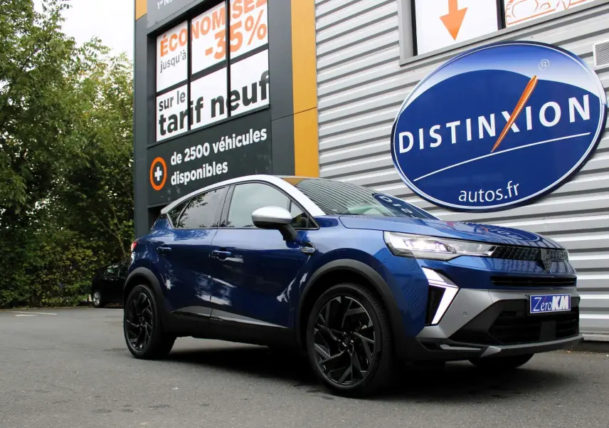 Renault Captur 2025 bleu Iron Metal avec toit gris, vue 3/4 avant droit, jantes noires et phares allumés.