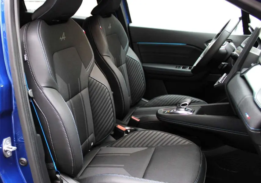 Intérieur côté conducteur du Renault Captur 2025 bleu iron metal, sièges noirs avec surpiqûres bleues et logo Alpine brodé.