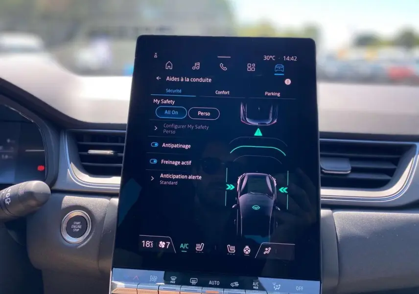 Écran tactile central du tableau de bord du Renault Captur 1.6 E-TECH hybride 2025 avec commandes de sécurité et climatisation.