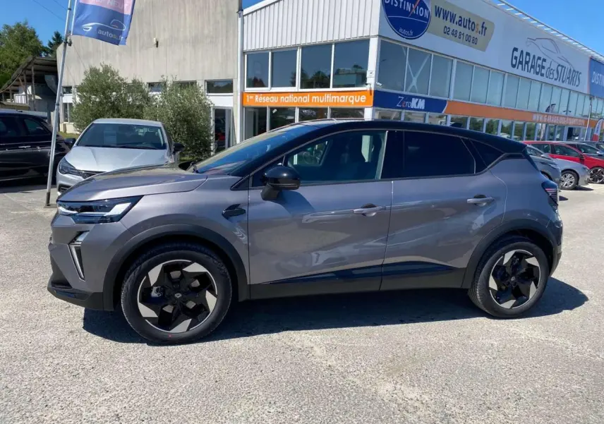 Profil côté gauche du Renault Captur 2025 gris Cassiopée avec toit noir et jantes aluminium noires sur parking.