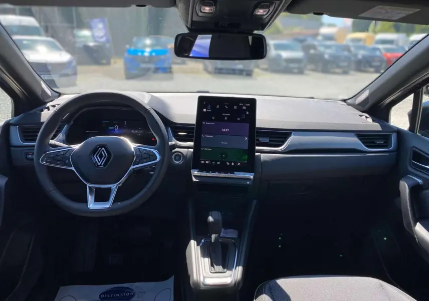 Vue intérieure du tableau de bord et volant Renault Captur 2025 avec écran tactile vertical et levier de boîte automatique.