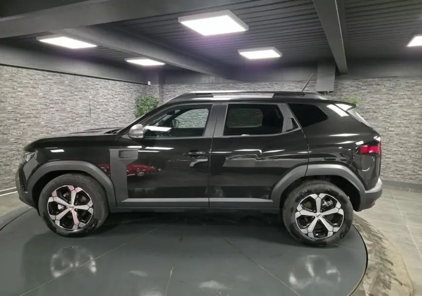 Vue de profil côté gauche du Dacia Duster 1.6 Hybrid 140 Journey noir nacré avec jantes alliage 18 pouces diamantées.