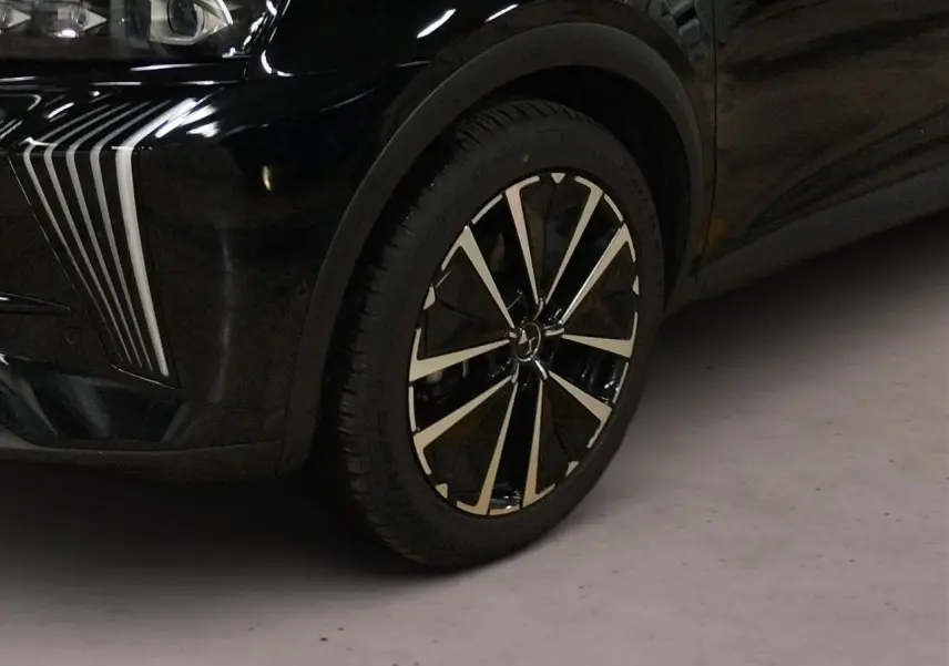 Gros plan sur la roue avant droite et le pare-chocs avant noir Perla du DS7 avec détails chromés verticaux.