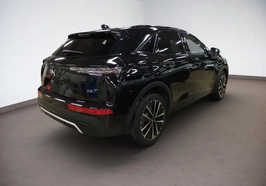 Vue 3/4 arrière droite d'un DS7 noir Perla avec jantes alliage et feux arrière LED 3D dans un intérieur neutre.