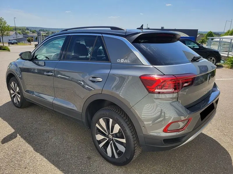 Vue 3/4 arrière droite d'un Volkswagen T-Roc gris Indium avec attelage amovible et jantes alliage bicolores.