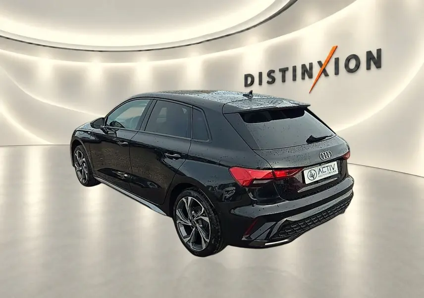 Audi A3 Sportback noir mythos vue 3/4 arrière droit avec jantes alu gris graphite dans un showroom lumineux.