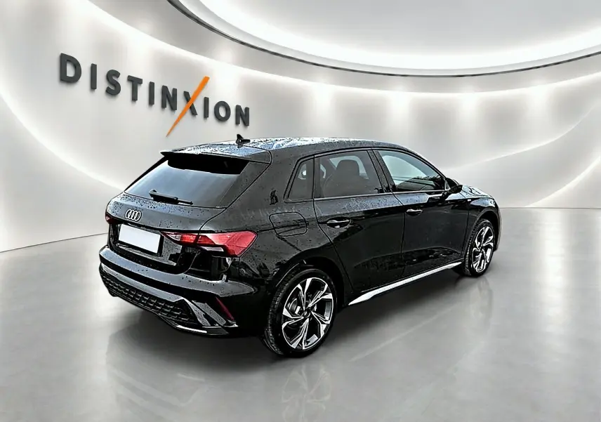 Audi A3 Sportback noir mythos vue 3/4 arrière droit dans un showroom lumineux avec jantes alu distinctives.