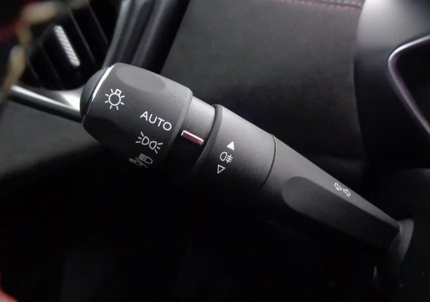 Gros plan sur la commande des phares et clignotants à gauche du volant dans l'habitacle noir du DS3 Crossback gris platinium.