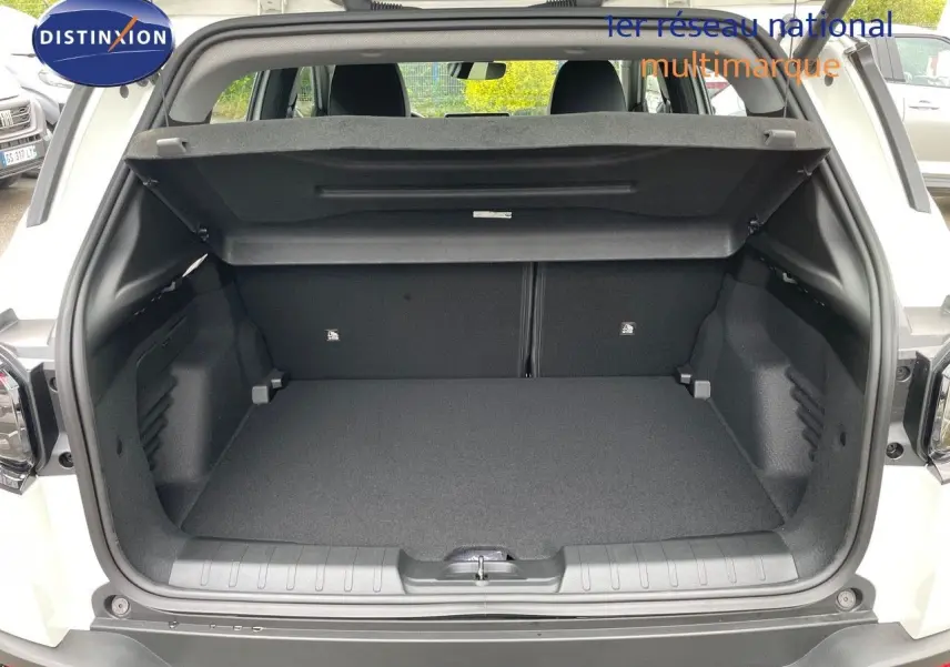 Coffre ouvert d'un Jeep Avenger blanc neige 2024, vue arrière montrant l'espace de chargement vide et la plage arrière relevée.