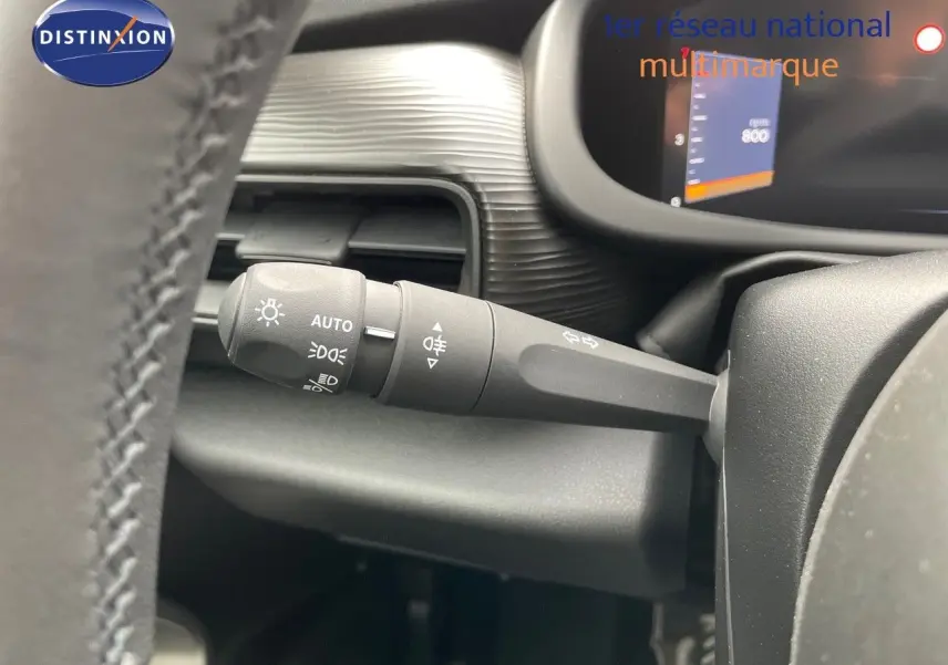 Gros plan sur la manette des feux et clignotants à gauche du volant dans l'habitacle du Jeep Avenger blanc neige 2024.