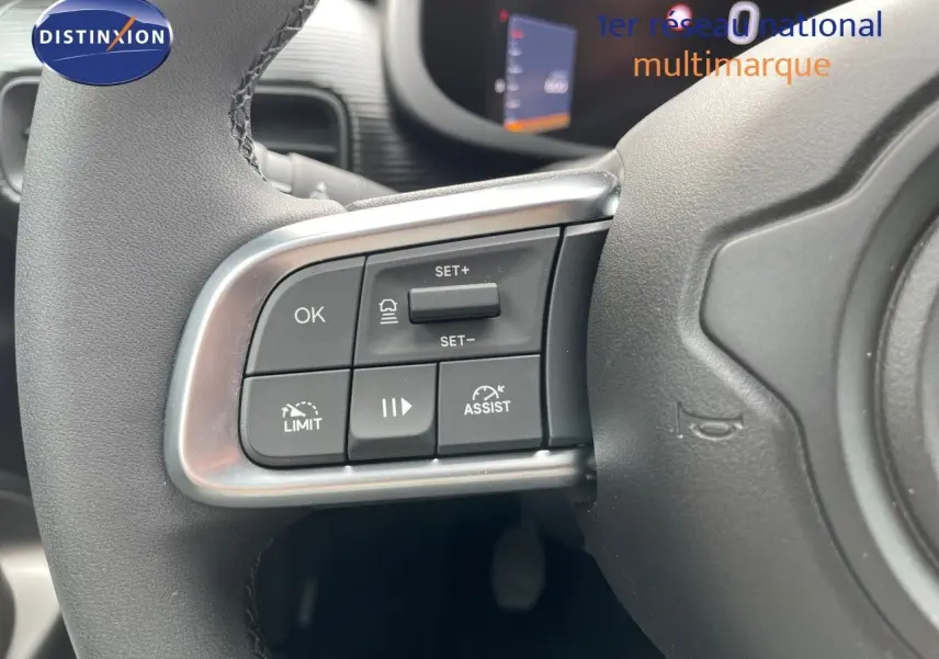 Gros plan sur les commandes au volant à gauche d'un Jeep Avenger blanc neige 2024, avec boutons de régulateur et assistances.