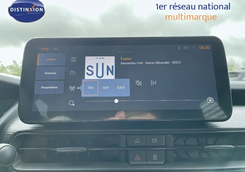 Écran tactile central du Jeep Avenger blanc neige 2024 affichant la radio FM avec la chanson Faster de Samantha Fish.