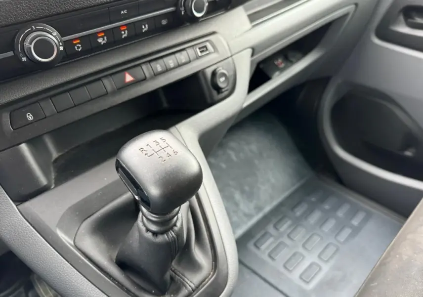 Gros plan sur le levier de vitesses manuel noir et la console centrale grise du Toyota Proace Fourgon blanc de 2021.