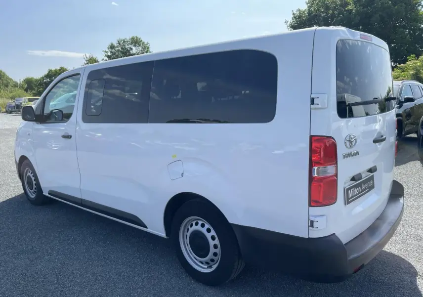 Vue 3/4 arrière droite d'un Toyota Proace Fourgon blanc avec vitres arrière teintées et pare-chocs noirs.