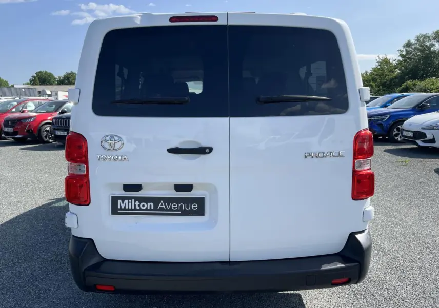 Vue arrière d'un Toyota Proace Fourgon blanc avec portes battantes vitrées et pare-chocs noir en plastique.