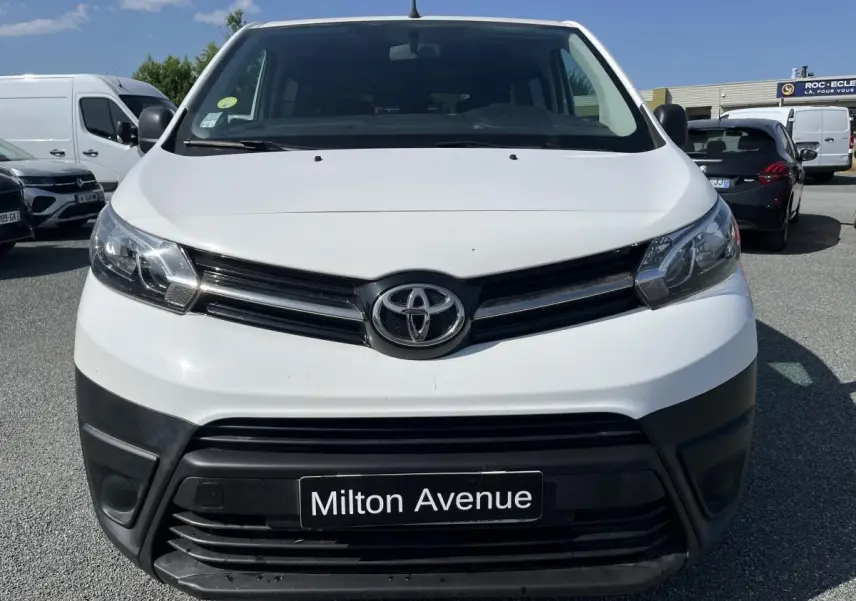 Vue frontale d'un Toyota Proace Fourgon blanc avec pare-chocs noirs et plaque Milton Avenue visible.