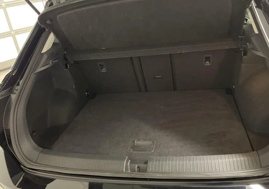 Coffre ouvert d'un Volkswagen T-Roc 2024 noir intense nacré, vue arrière montrant l'espace de chargement vide.