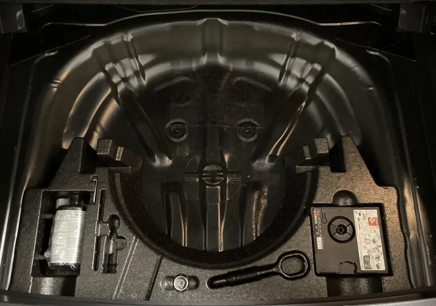 Compartiment de rangement sous coffre noir du Volkswagen T-Roc 2024 avec kit de réparation pneus intégré.