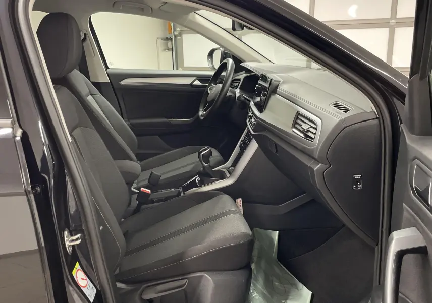 Intérieur côté conducteur du Volkswagen T-Roc 2024 noir intense nacré, montrant sièges et tableau de bord moderne.