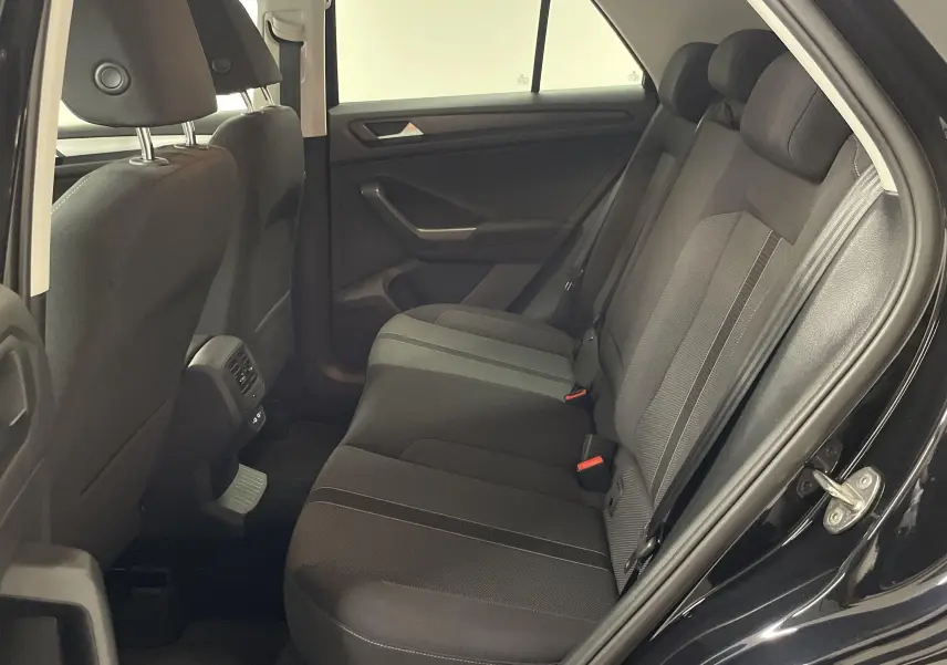 Vue intérieure côté droit des sièges arrière noirs du Volkswagen T-Roc 1.5 TSI 2024 avec tissu et ceintures visibles.