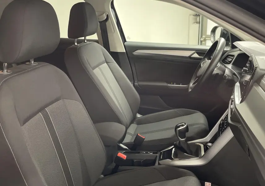 Vue intérieure côté conducteur du Volkswagen T-Roc 2024 avec sièges tissu gris et console centrale moderne.