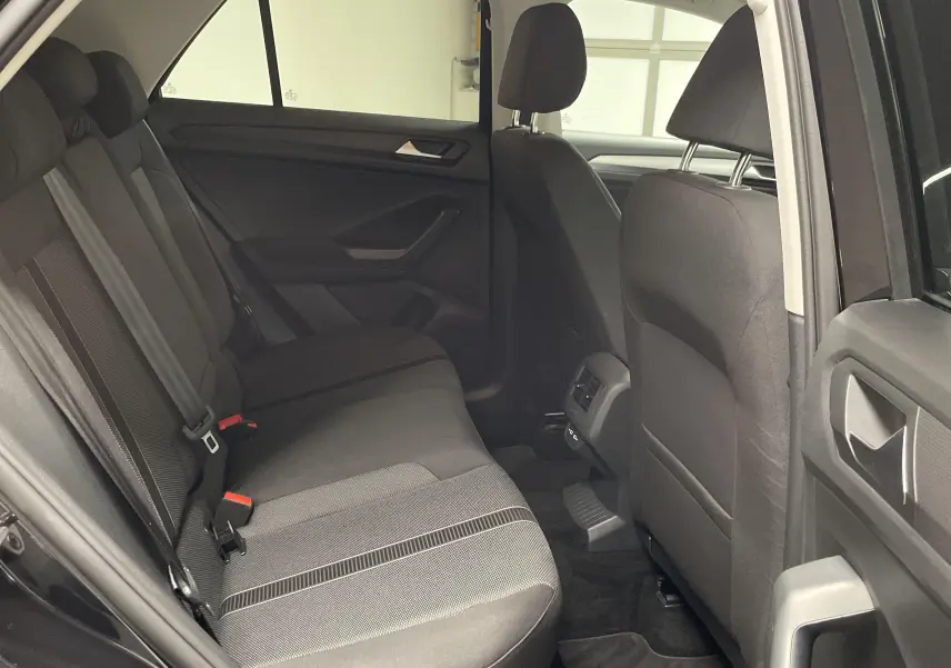 Vue intérieure côté gauche sur les sièges arrière noirs du Volkswagen T-Roc 2024 avec portières ouvertes.