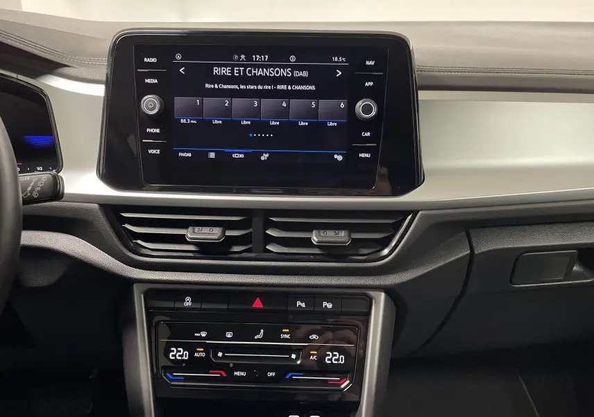 Vue intérieure du tableau de bord du Volkswagen T-Roc 2024 avec écran tactile et commandes climatisation digitales.