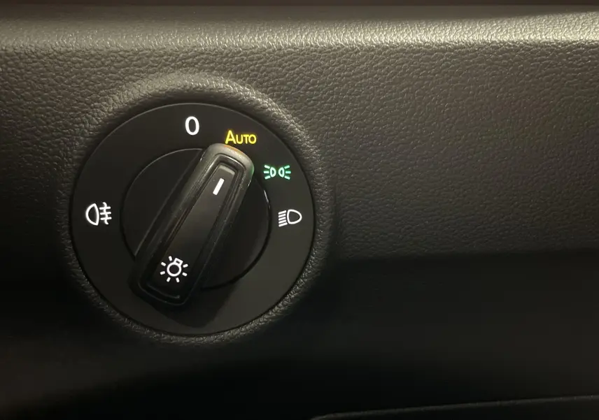 Gros plan sur le sélecteur de phares du Volkswagen T-Roc 2024, finition Noir Intense nacré, avec mode automatique activé.