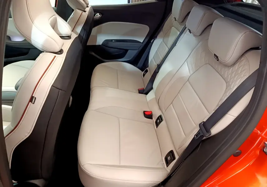 Vue côté droit de la banquette arrière beige clair de la Renault Clio Initiale Paris orange, avec finitions élégantes et ceintures noires.
