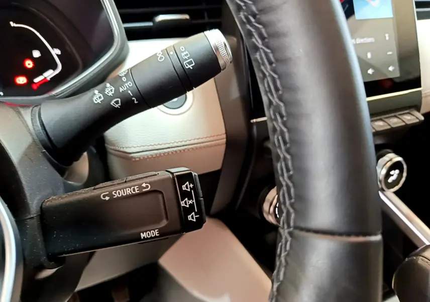 Gros plan sur la commande multimédia et le volant en cuir noir de la Renault Clio Initiale Paris orange 2021.