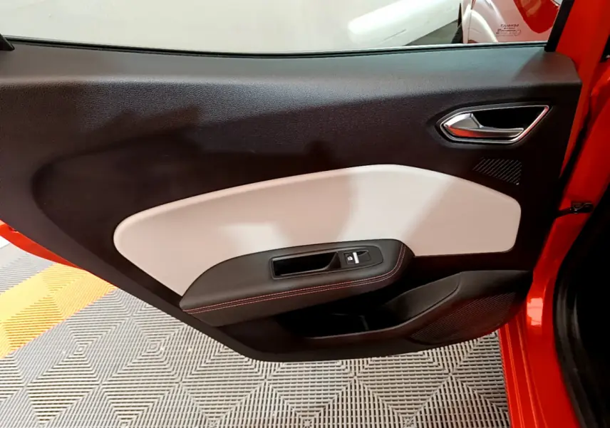 Porte côté gauche ouverte de la Renault Clio Initiale Paris orange, intérieur noir et beige avec surpiqûres rouges.
