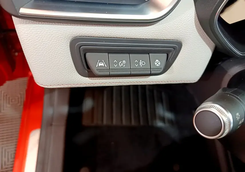 Gros plan sur les commandes d'assistance et éclairage à gauche du volant dans l'habitacle d'une Renault Clio orange 2021.