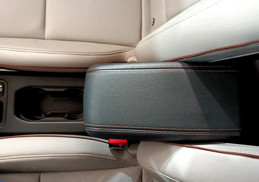 Vue plongeante sur l'accoudoir noir avec surpiqûres orange et sièges cuir beige de la Renault Clio Initiale Paris E-TECH 2021