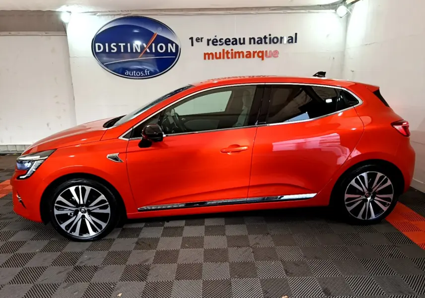 Profil côté gauche d'une Renault Clio Initiale Paris E-TECH 140 orange, avec jantes alliage et rétroviseurs noirs.