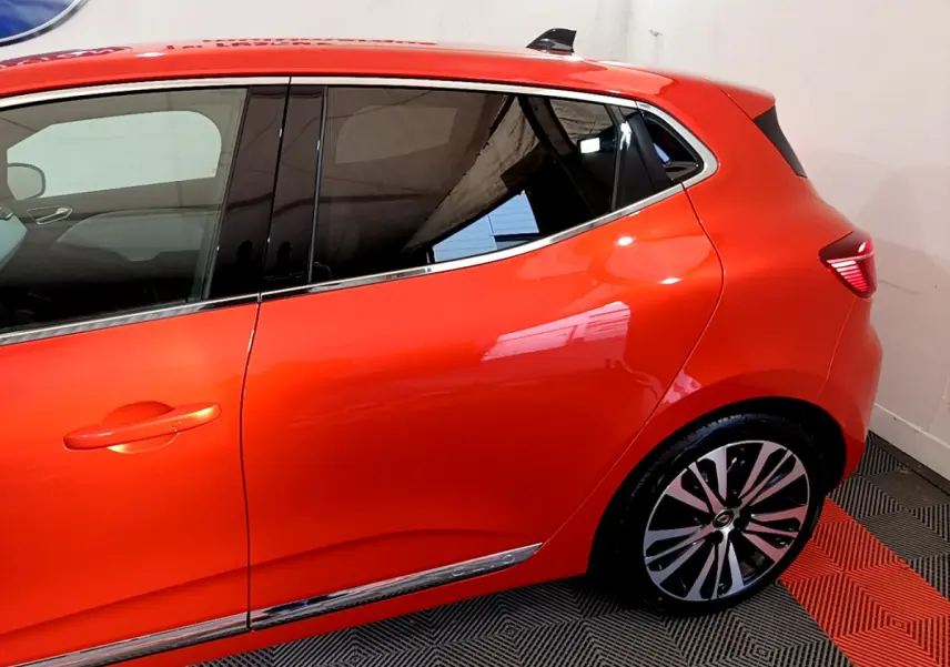 Profil côté gauche de la Renault Clio Initiale Paris orange 2021, mettant en valeur la jante alliage et les vitres teintées.