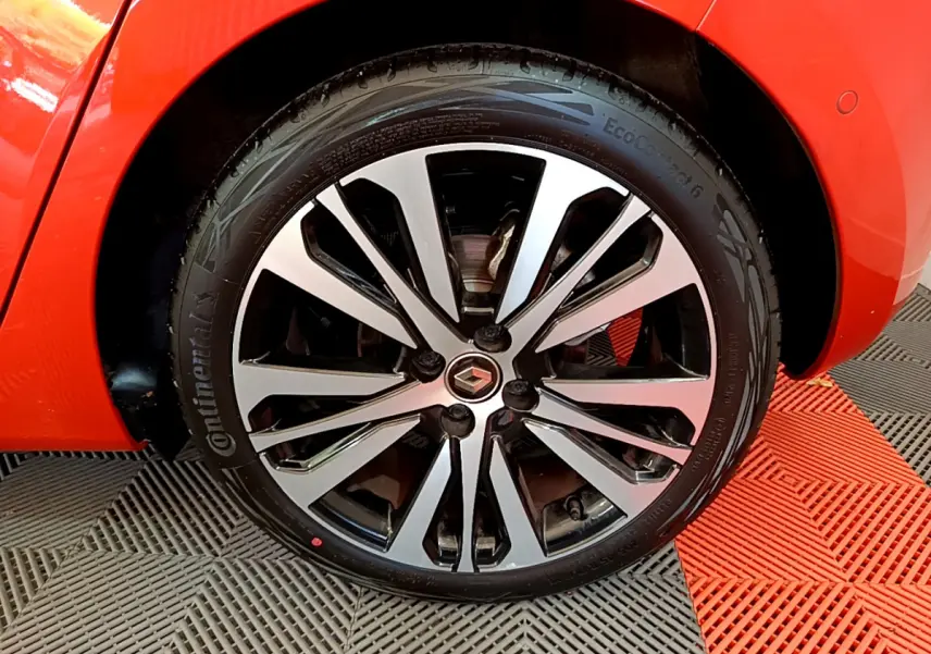 Gros plan sur la roue avant droite orange d'une Renault Clio Initiale Paris E-TECH 140 avec jante alliage bicolore